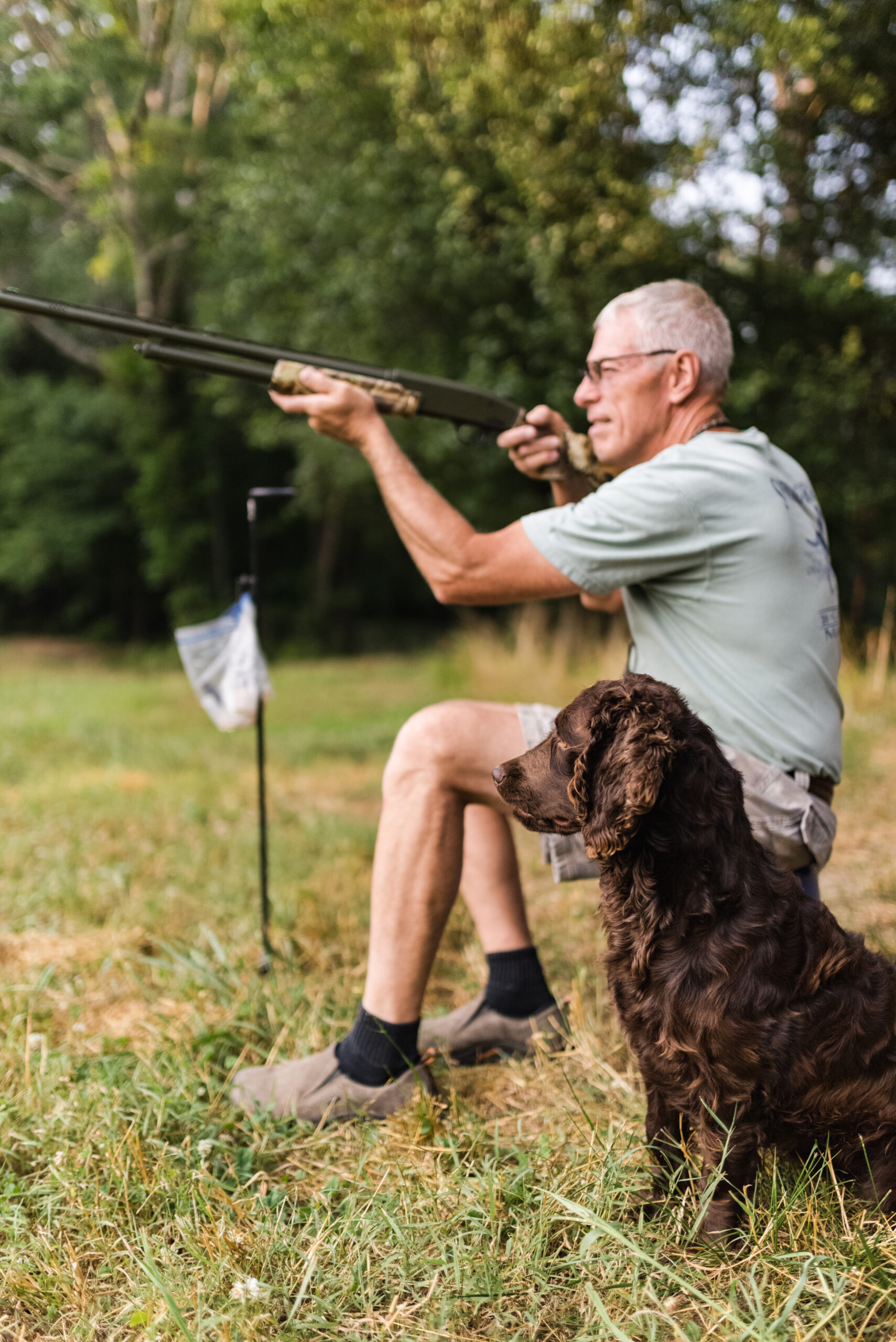 dog sitting by man holding a firearm | StormRyder Kennels Dog Training